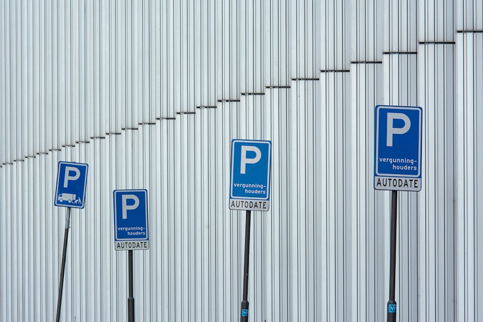 Close-up image of a parking meter situated on a pavement in Woolwich, featuring a predominantly grey body with a large blue 'P' symbol on the side indicating parking. The digital display on the meter shows parking payment details, including a start time of 8:00 and an end time of 18:00 from Monday to Friday, with information about free parking on weekends. The front panel includes operating instructions, a keypad with numbers and function keys, and a small screen displaying transaction information. In the background, blurred residential buildings and greenery suggest an urban neighbourhood environment. This parking meter, used for managing parking permits during home relocation or furniture transport, is associated with Woolwich Council parking regulations. Occasionally, professional removal teams, like those from Man With a Van Woolwich, utilize such parking options when carrying out house removals and moving services within the area, ensuring compliance with local parking policies during loading and unloading processes.